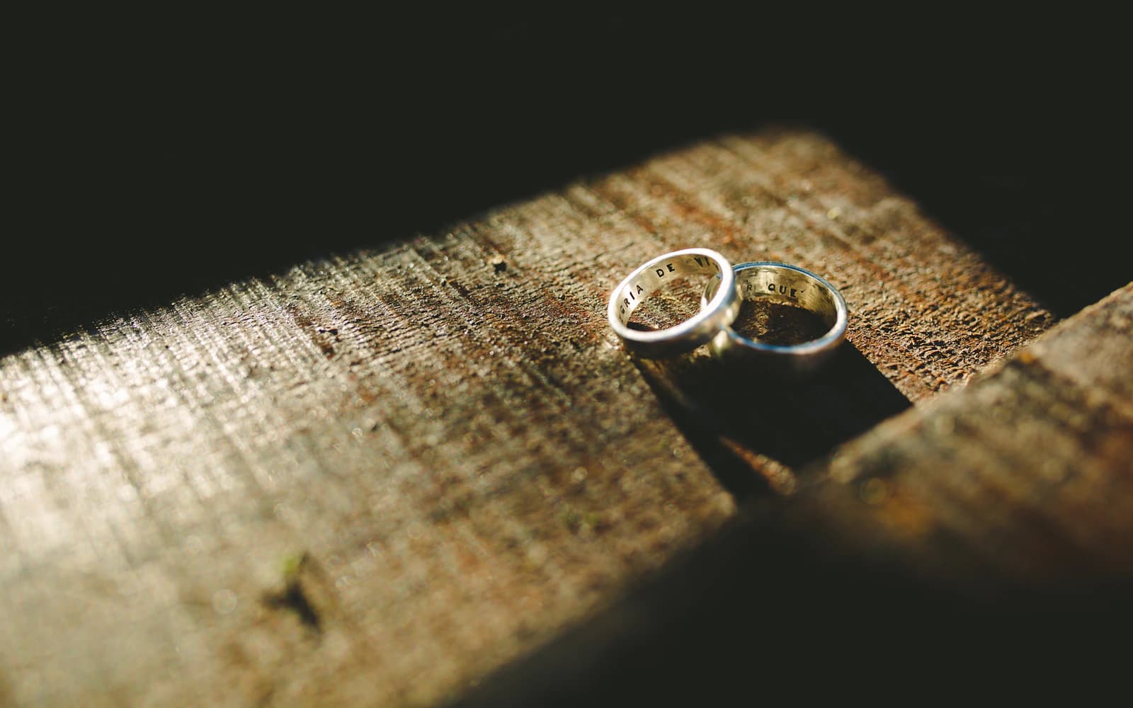 Two silver engagement rings resting on a wooden surface
