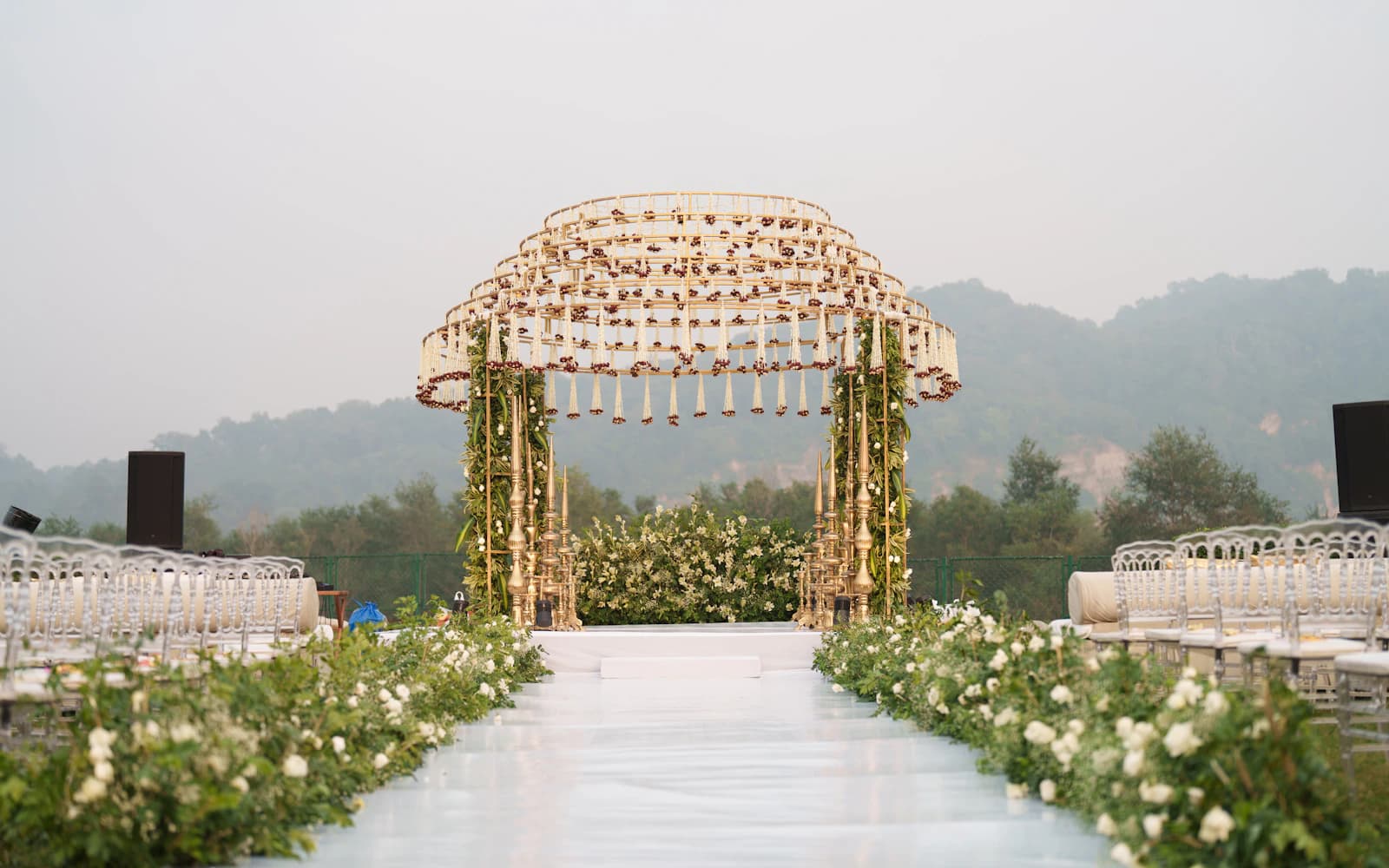 Wedding ceremony seating beside a floral aisle and decorated arch